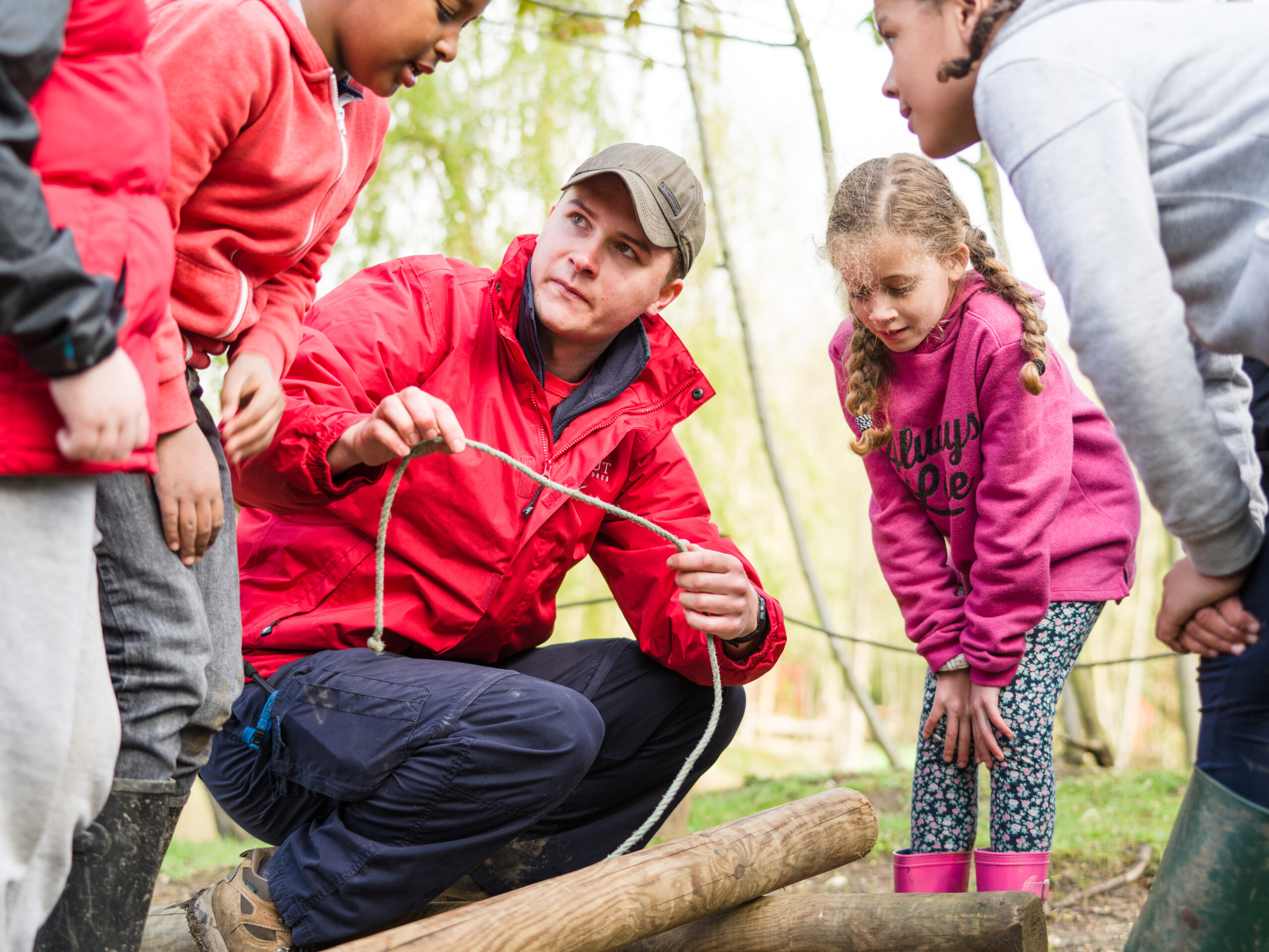 an adult leader teaching rope skills to three young people