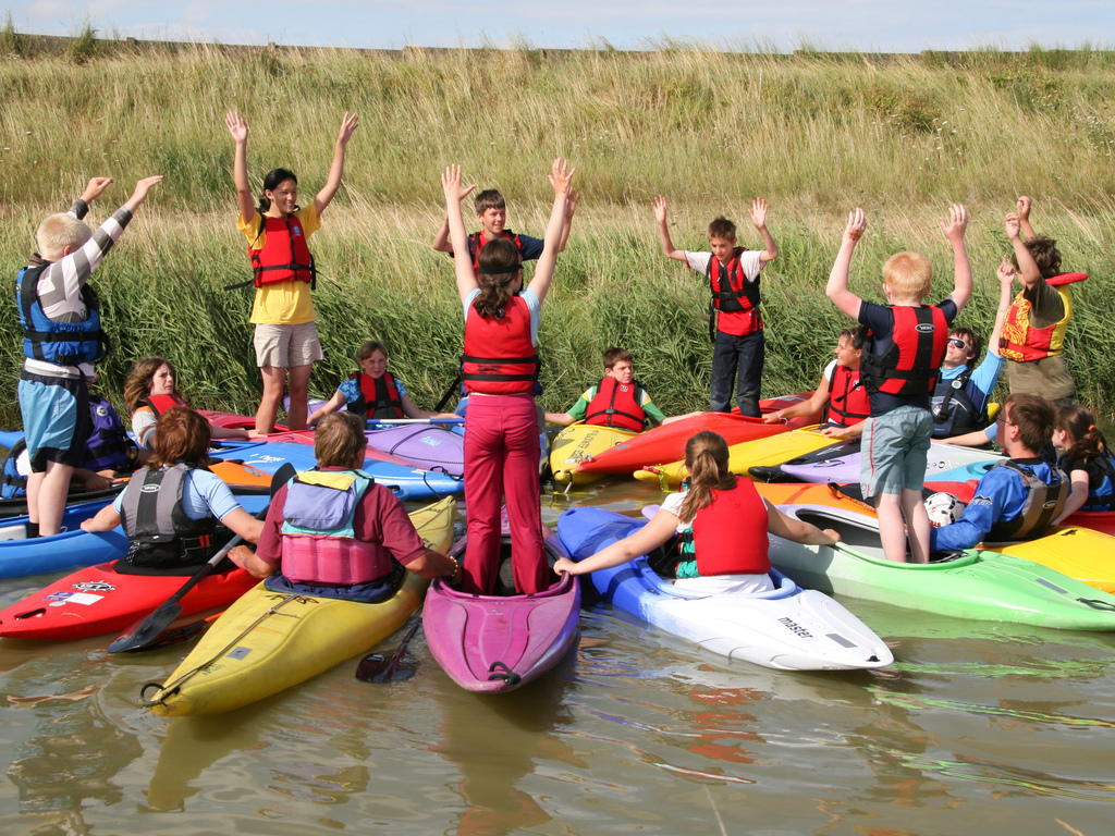 a circle of young people in kayaks playing a game